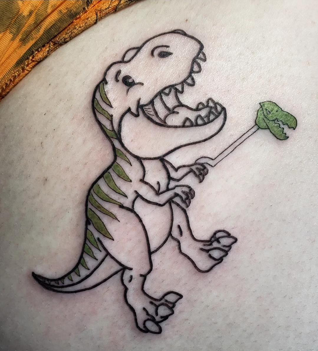 Black and grey stylized tattoo of a dinosaur holding a green dinosaur toy.