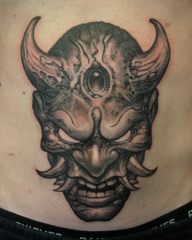 Stomach tattoo of a demon head done in fine line black and grey ink by Shaine Smith of Sacred Mandala Studio.