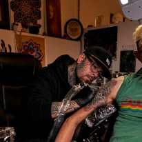 Photograph of tattoo artist Alan Lott working on a mandala dot bicep tattoo at Sacred Mandala Studio in Durham, NC.