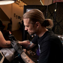 Photograph of tattoo artist John Campbell at Sacred Mandala Studio - working on a tattoo.