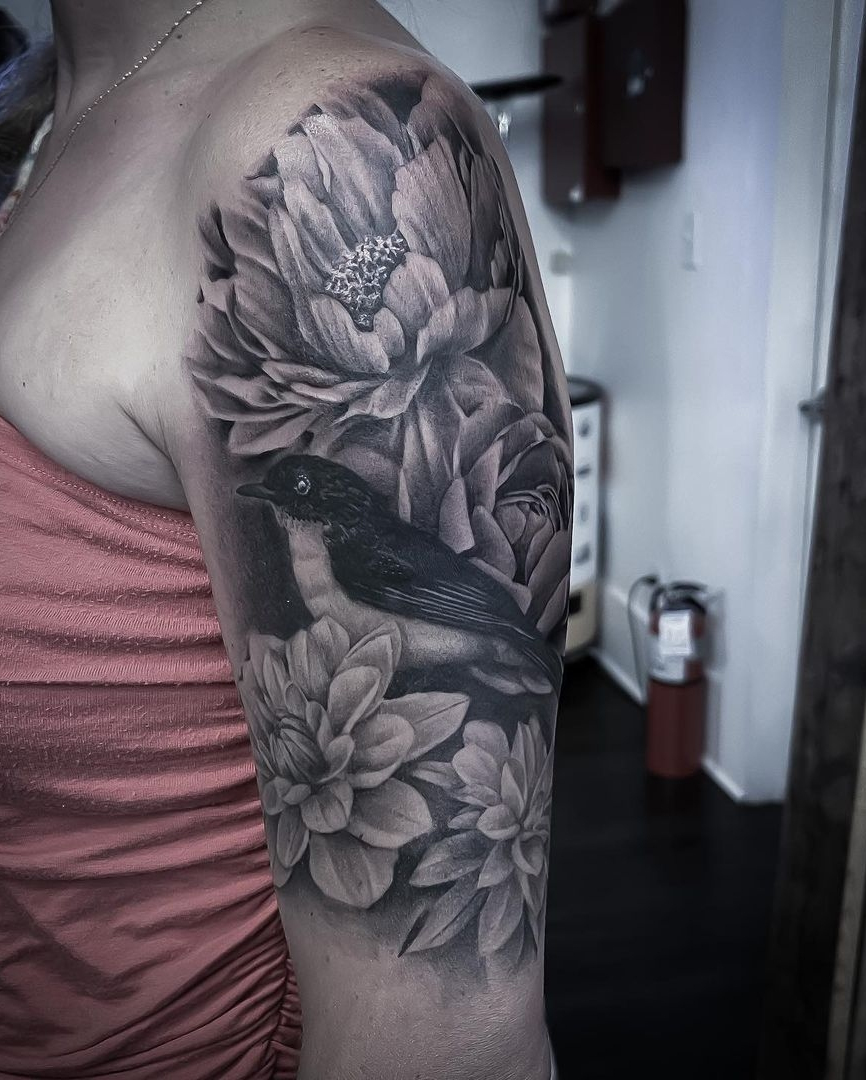 Shoulder and upper arm tattoo - fine line black and grey tattoo by artist Alan Lott of Sacred Mandala Studio. Tattoo of a bird surrounded by peony, dahlia and rose flowers.